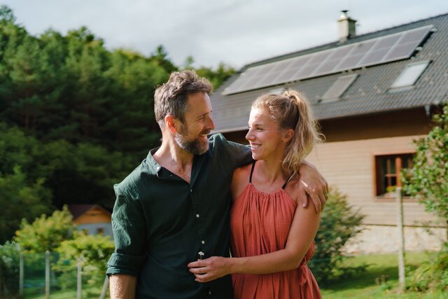 Ein Mann und eine Frau, die vor einem Haus stehen.