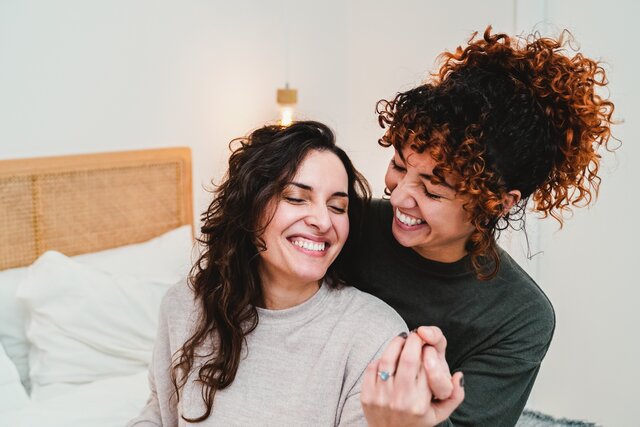 Zwei Frauen, die Händchen halten und lächeln.